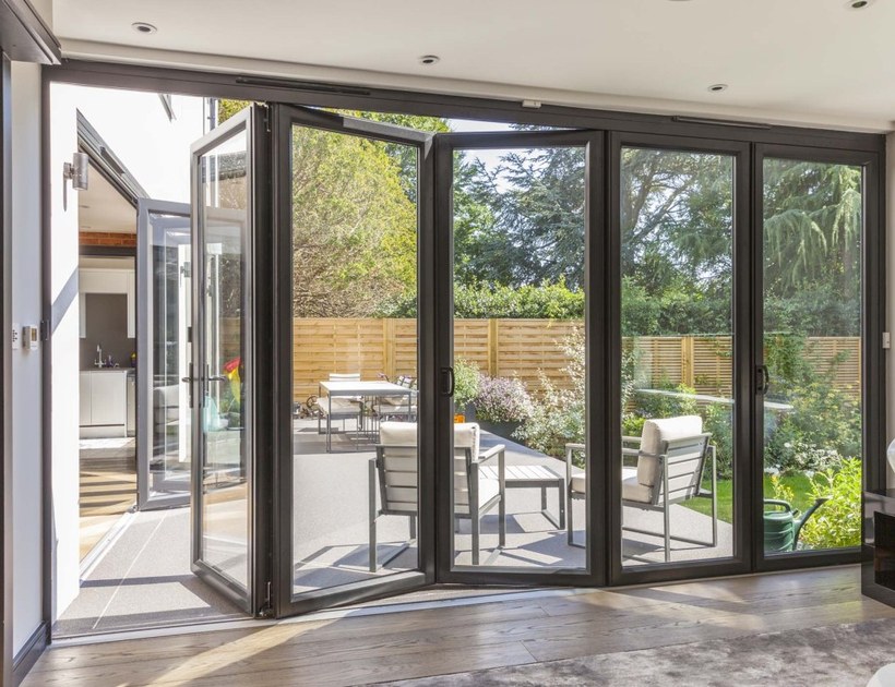 PRM-75 Series aluminum bi-fold door open to patio with outdoor seating