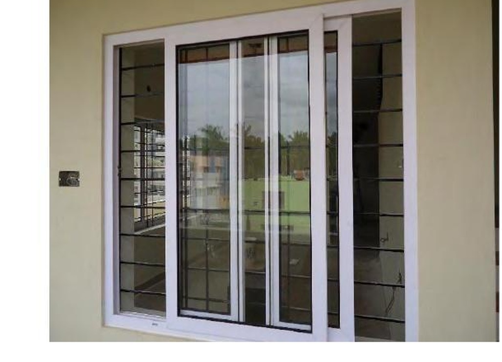 White uPVC sliding window with decorative grille on warm-toned exterior wall